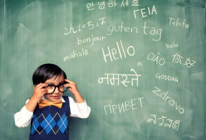 Child learning multiple languages written on a chalkboard.