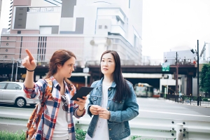 Two women communicating in an urban setting, illustrating the importance of overcoming language barriers in education.